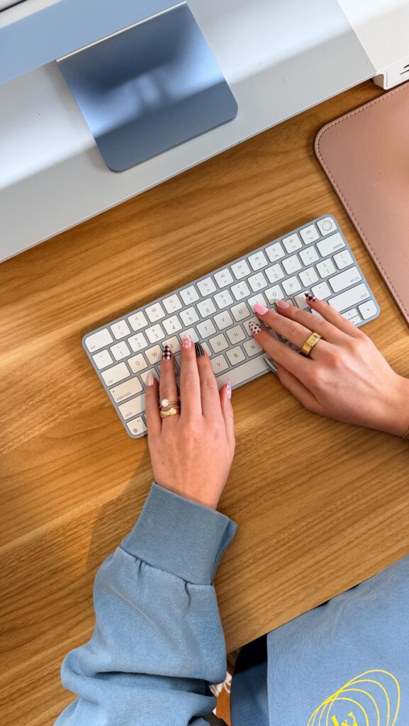 Manicured hands on keyboard showcasing how to design logo ideas for interior designers. 